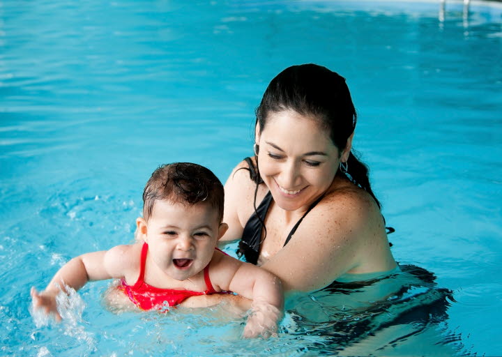 A mother bathing in a pool with her baby.