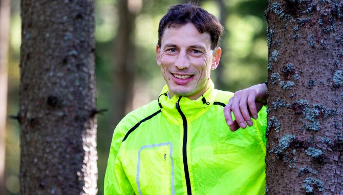 Glad kille står lutad mot ett träd.