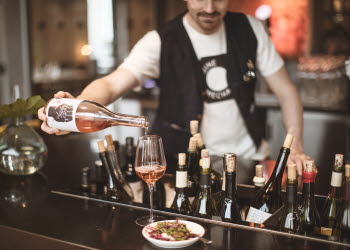 A man pouring up a glass of wine in a bar