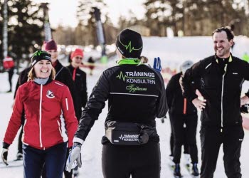 Glada skidåkare i grupp tränar stakåkning utan stavar med ledare
