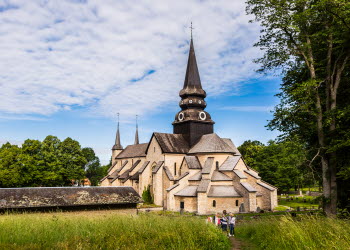 Varnhems klosterkyrka. I förgrunden syns vandrare gå mot den imponerande stenkyrkan.