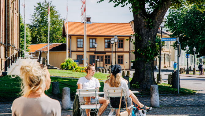 Tre personer sitter på ett utecafé och det är sommar ute