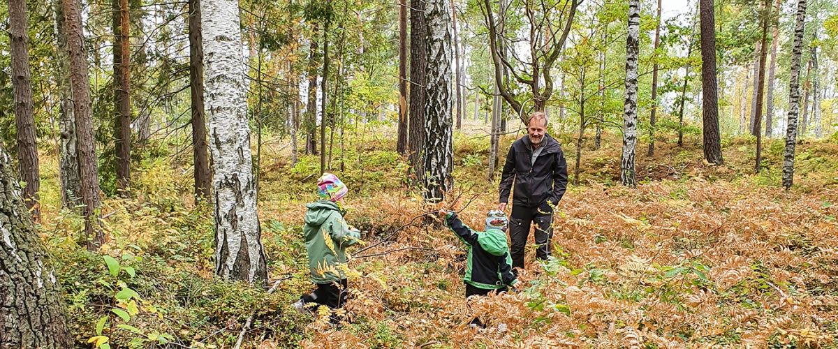 En vuxen person och två barn i en skog.