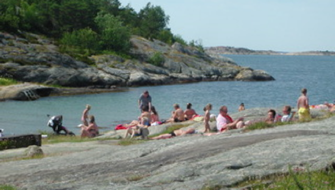 Badgäster har samlats på en klipphäll på Furholmen. Holmen är en populär badplats och nås genom en ungefär fem minuter lång båtresa.