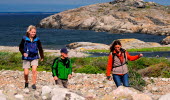 Three people are hiking across a cobblestone field at North Koster.