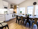 Kitchen with white doors and white walls. Dining room with concrete table and gray metal chairs.