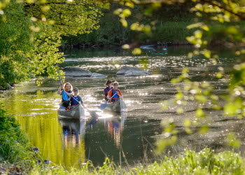 En bild på två kanoter som flyter på en glittrande å