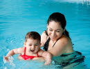 En mamma som badar i en pool med sin baby.