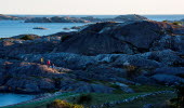 Three paople are hiking along a large cliff at North Koster. 