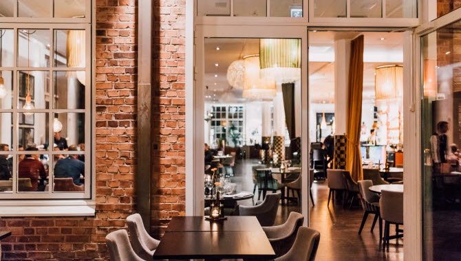 A nice and decorated dining room with brick walls and large windows.