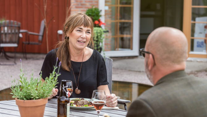 Man och kvinna som sitter och pratar medan de äter mat på en uteservering.