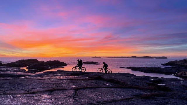 MTB-cyklister på klippa i solnedgång