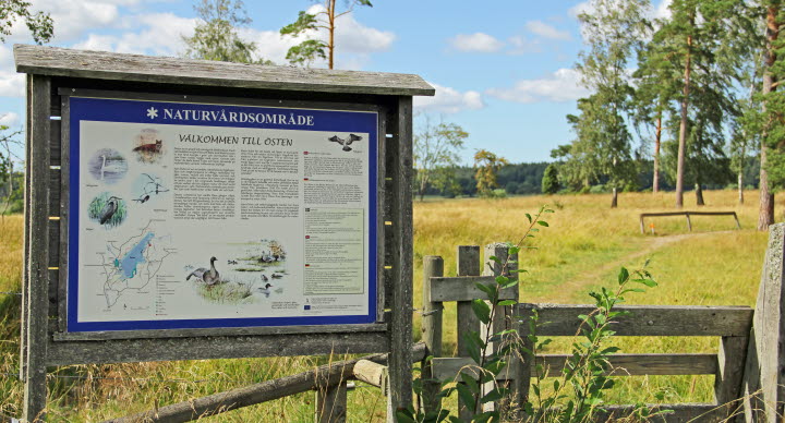 Informationsskylt, utomhus i naturen, för naturreservat sjön Östen.