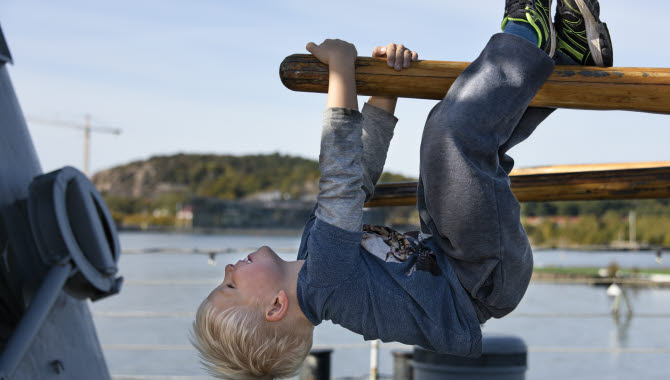 Pojke hänger upp och ned på Maritiman.