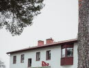 A photo of an apartment building with a cinema entrance centrally located on the front of the building. In the foreground, a tall pine tree partially obscures the building.