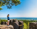 Ung kvinna står vid kanten av de stora diabaspelarna vid Ryds grottor och njuter av den blåa himmelen och den vackra utsikten. 