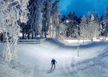 Skidåkare svischar förbi i spåren en vinterkväll på Billingen Skövde. 