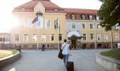 Woman walks towards hotel building.