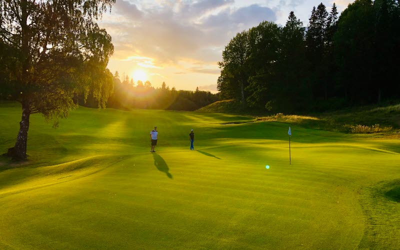 Skövde golfklubb, två peroner som spelar golf i solnedgång