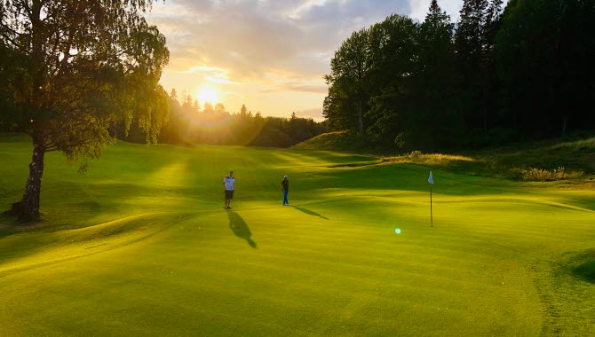 Skövde golfklubb, två peroner som spelar golf i solnedgång
