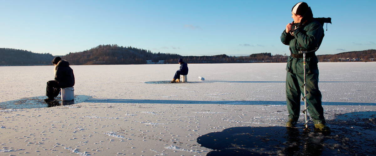 Tre personer fiskar på is