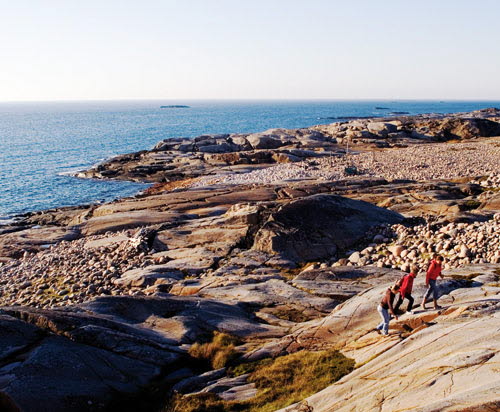 Tre personer vandrar över en klippa på Nordkoster, omgivna av klapperstensfält. 