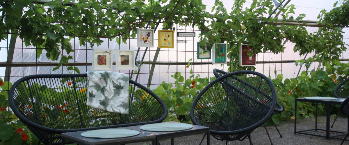 Bord och stolar att fika vid i växthuset på Närebo gårdsbutik, restaurang och hotell. 