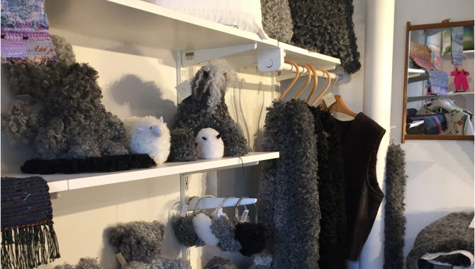 Här kan du se flera olika hantverk tillverkade i ull. Tröjor, får och kuddar