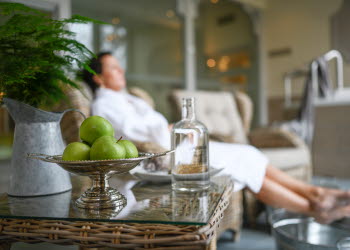 Man som sitter i morgonrock och vilar sig. Äpplen ligger i en skål.