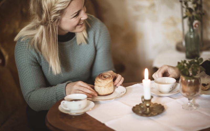Kvinna fikar på kanelbulle och kaffe