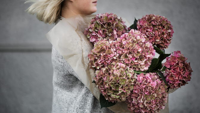 Girl holding several flower arrangements.