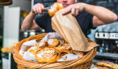 Caféägare lägger i nybakta bullar i en påse. 