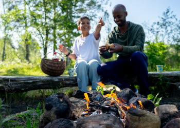 En pappa och ett barn grillar marshmallows över öppen eld.