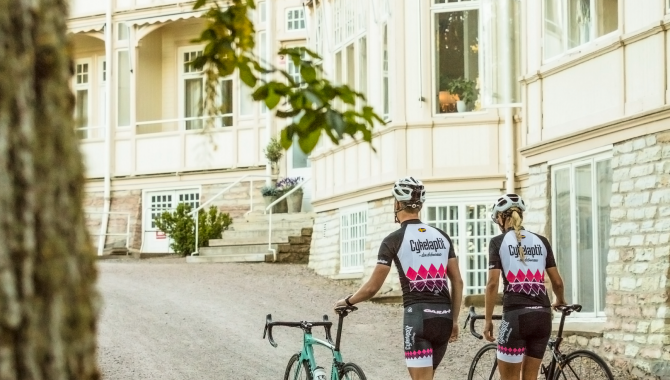 Kvinna och man som leder sina cyklar utan för Kurorten.