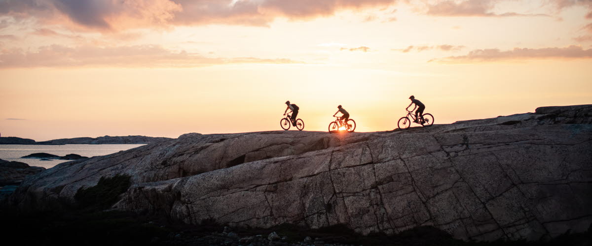 MTB-cyclists on the smooth rocks in Bohuslän with an amazing sunset as a backdrop