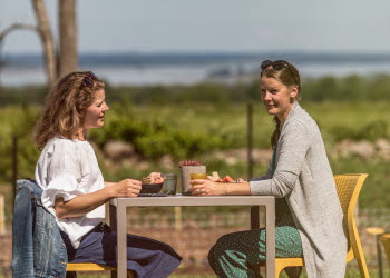 Två kvinnor som sitter på uteserveringen och fikar.