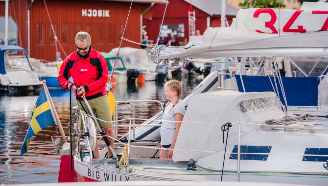 Två personer på en segelbåt i Hjo hamn.