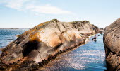 A person in a kayak is paddeling through a narrow canal between two cliffs. 