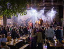 A band playing on an outdoor stage during a festival infornt of a big crowd