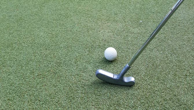 Golfklubba och boll som ska skjuta mot ett hål.