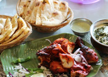 En närbild på en portion indisk mat som ligger upplagt snyggt på tallrik.