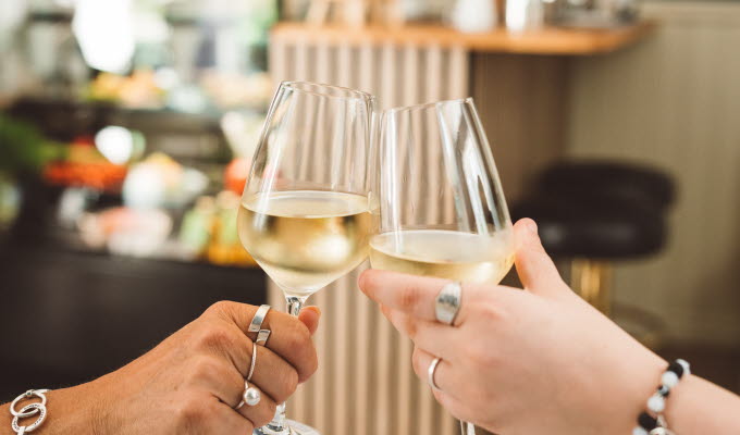 Två människor skålar i bubbel vid ett dukat bord.
