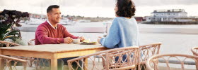 A man and woman enjoy breakfast next to the sea