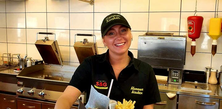 Hammarkioskens personal håller upp en bricka med pommes, dricka och hamburgare.