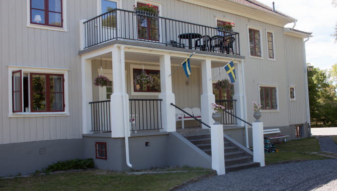 Entrén på Pensionat Klåvasten, en större vit träbyggnad med röda fönster.
