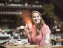 Woman sitting and smiling with a glass of wine in her hand