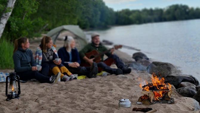 Ett gäng ungdomar fricampar på en strand.