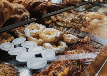 En närbild på utbudet av bullar, kakor och bakelser i en cafédisk