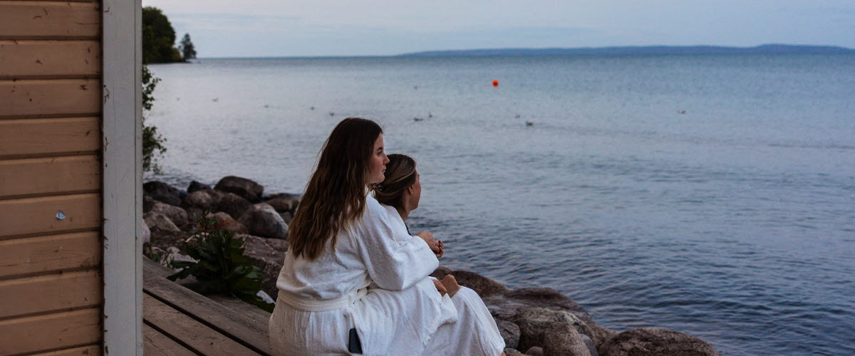 En grupp personer njuter av bastun vid Vätterns strand i Hjo