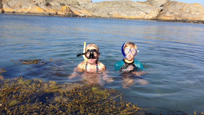 Två barn badar i havet och har snorkel på sig.